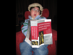 Adam wearing barrister wig and holding human rights text book